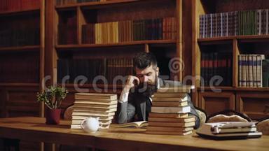 严肃的男学生在图书馆看书。 有胡子的人在书架背景上看书。 经典男人